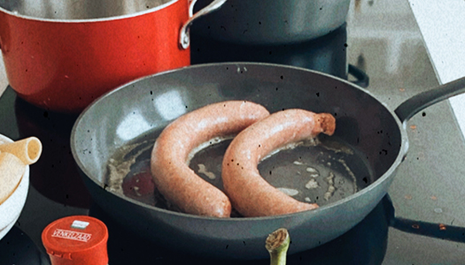 Foto van worsten die gebakken worden in de pan